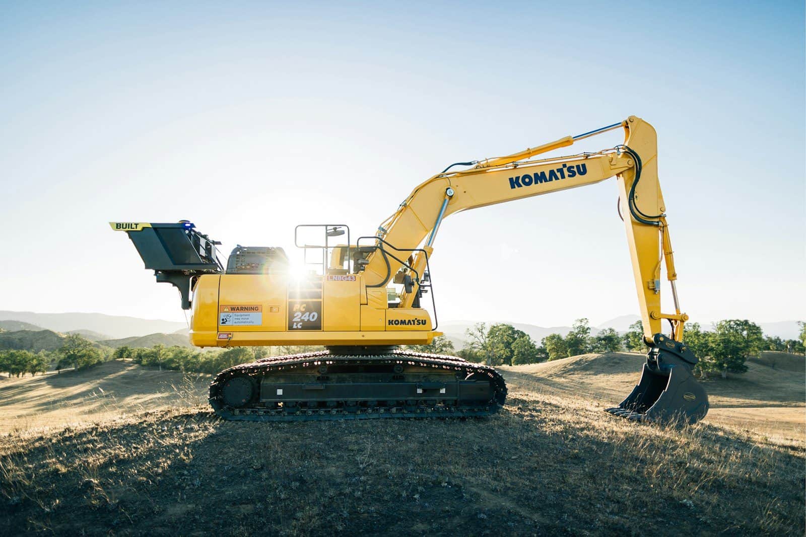 A tracked excavator with its bucket lowered on a working platform